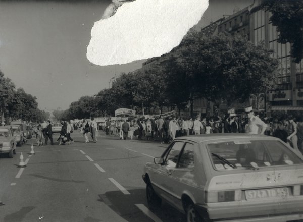 Chaussée avec foule et voitures.
