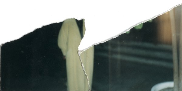 Individu en longue veste blanche. Image déchirée en partie reconstituée.