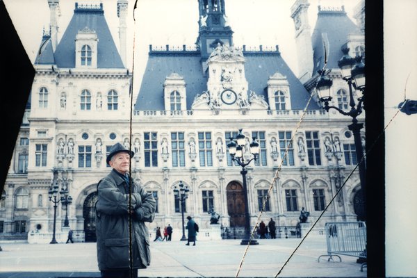 Homme devant un hôtel de ville orné de sculptures. Image avec déchirure, reconstituée.ᴬᴵ