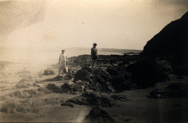 Deux personnes sur une plage rocheuse. Noir et blanc.ᴬᴵ
