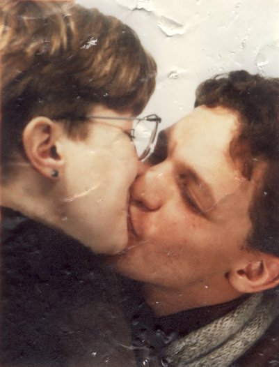 Baiser entre une jeune femme blonde à lunette et un jeune homme brun.