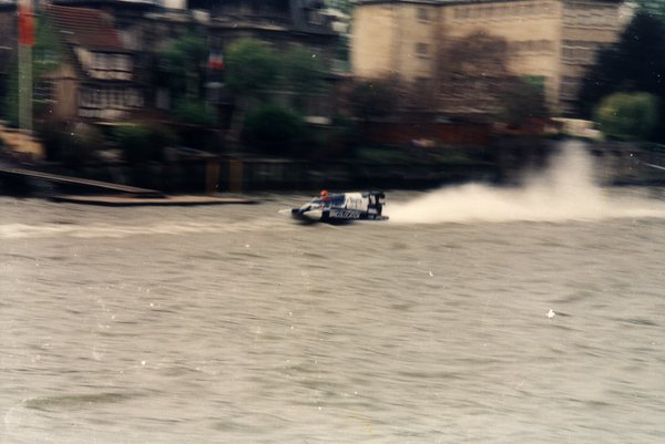 Bateau de course devant des maisons au bord de l'eau.ᴬᴵ