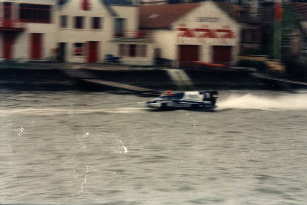 Bateau de course devant des maisons aux portes rouges.ᴬᴵ
