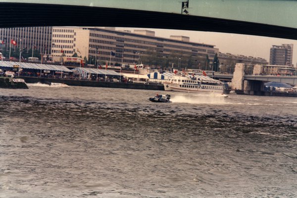 Bateau de course croisant un bateau de tourisme sous un pont en ville.ᴬᴵ