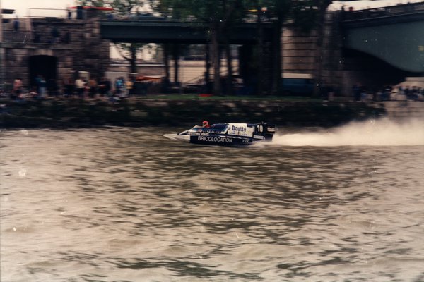 Bateau de course Boutté numéro 10 devant un mur de pierre avec spectateurs.ᴬᴵ