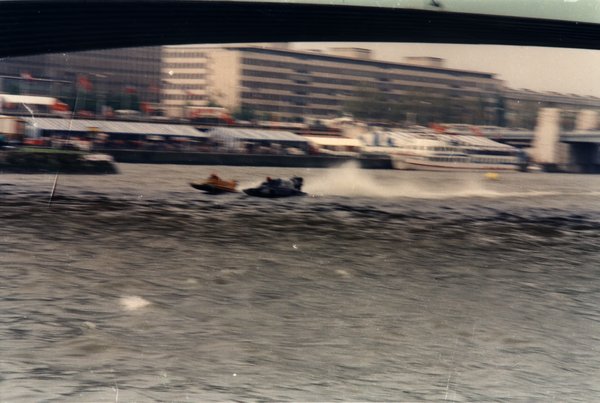 Deux bateaux de course côte à côte sous un pont en ville.ᴬᴵ
