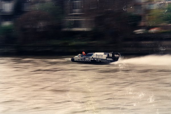 Bateau de course Boutté numéro 10 devant une rive bordée d'arbres.ᴬᴵ