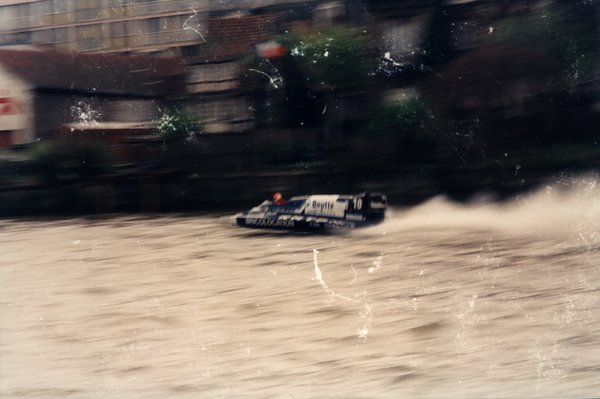 Bateau de course Boutté numéro 10 devant des bâtiments avec une enseigne rouge.ᴬᴵ
