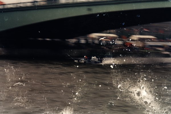 Bateau de course sous un pont, image marquée par de nombreuses éclaboussures et rayures.ᴬᴵ