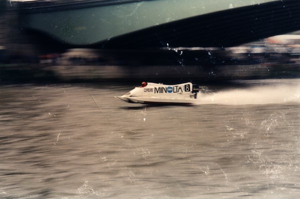 Bateau de course Minolta numéro 8 sous un pont.ᴬᴵ