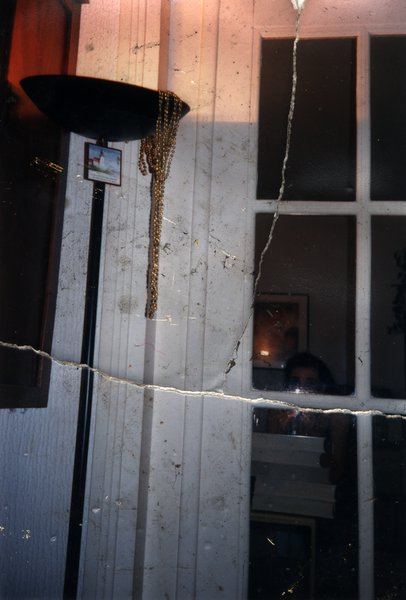Personne aperçue derrière une fenêtre à petits carreaux. Image avec pliure.ᴬᴵ