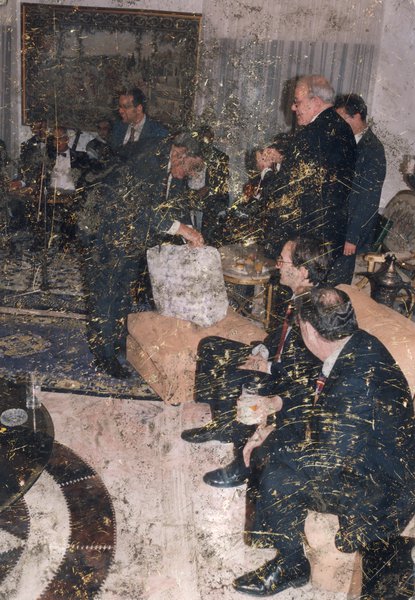 Assemblée d’hommes en complet bleu marine avec des verres à la main dans une salle de réception. Image avec rayures.