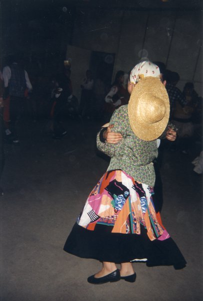 Femme de dos à jupe bariolée et chapeau de paille.