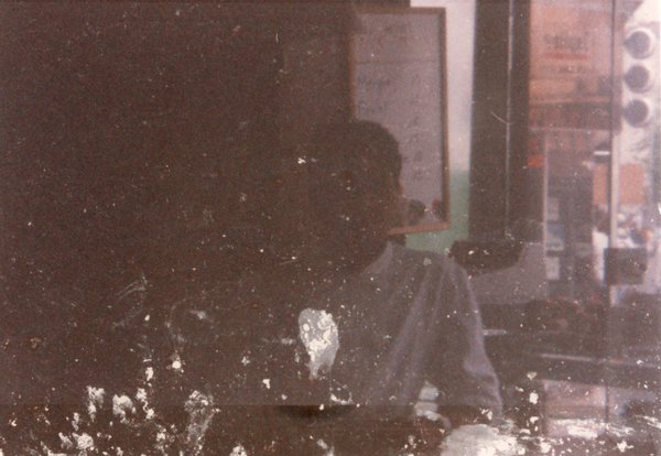 Homme brun en chemise blanche assis à une table.